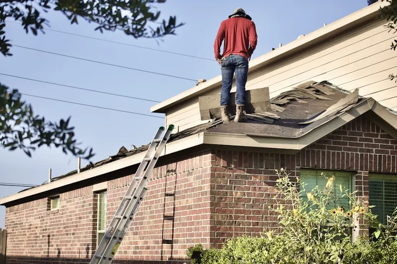 Professional roofer working on a residential roof in Paola